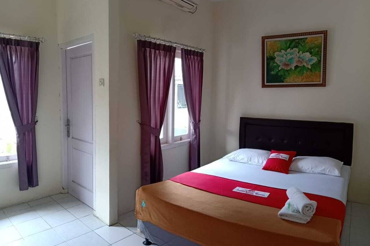 Ein Hotelzimmer mit einem Bett, einem Gemälde und Vorhängen.