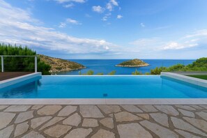 A swimming pool with a view of the sea and two islands.