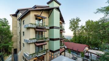 Un hotel de varios pisos con balcones, mobiliario exterior y vistas del paisaje circundante.