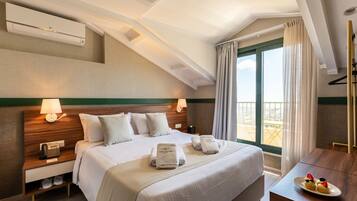 A hotel room with a large bed, a desk with a plate of food, a telephone, and a window with curtains.