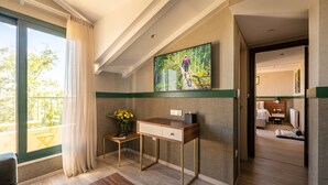 Una habitación de hotel moderna con un ventanal grande, un escritorio con un florero y un cuadro en la pared.