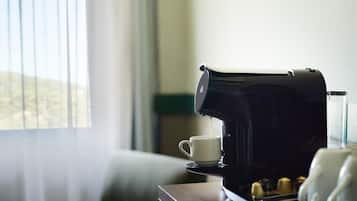 Una cafetera sobre una mesa con una taza y un vaso.