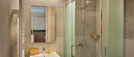 A bathroom with a sink, mirror, and shower.