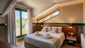 Habitación de hotel con una cama grande, una mesita de noche con lámpara y vistas al exterior a través de una ventana.