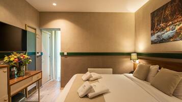 Habitación de hotel con cama, escritorio, televisor y un cuadro en la pared.