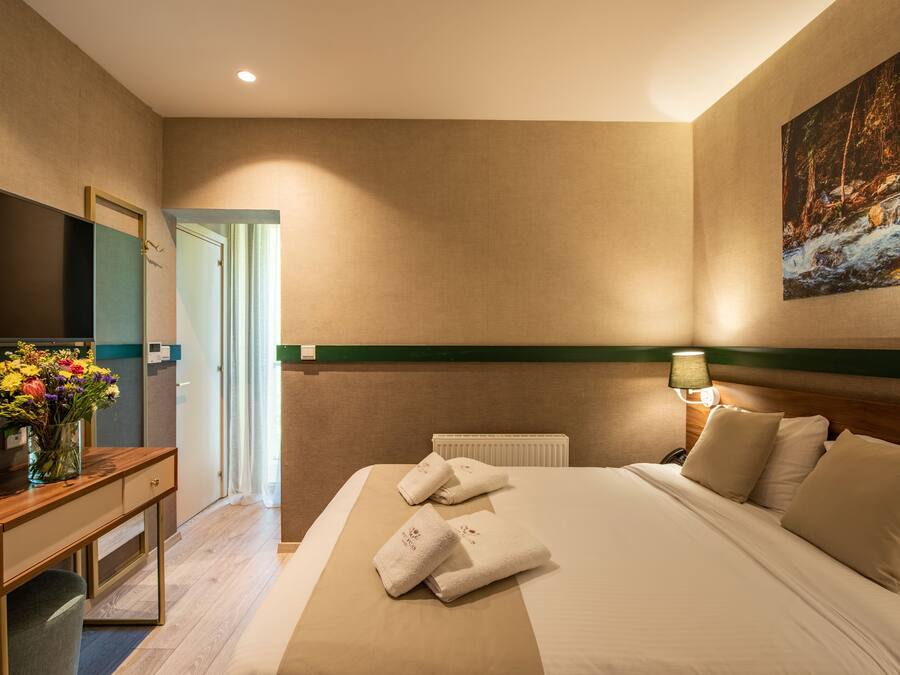 Habitación de hotel con cama, escritorio, televisor y un cuadro en la pared.