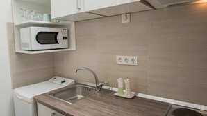 Een compacte keuken met een ingebouwde magnetron, een spoelbak en een klein aanrecht.