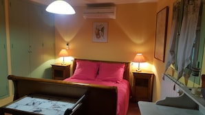 Una habitación con una cama de madera, dos lámparas de noche, aire acondicionado y un cuadro en la pared.