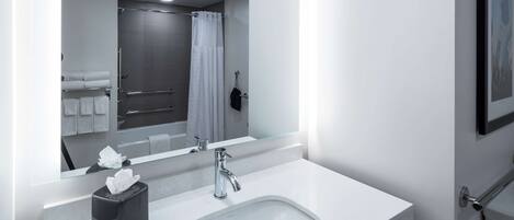 A modern bathroom with a white sink, a glass shower enclosure, and a large mirror.