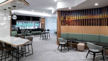 A modern restaurant with a bar area, seating arrangements, and a large wall mural.