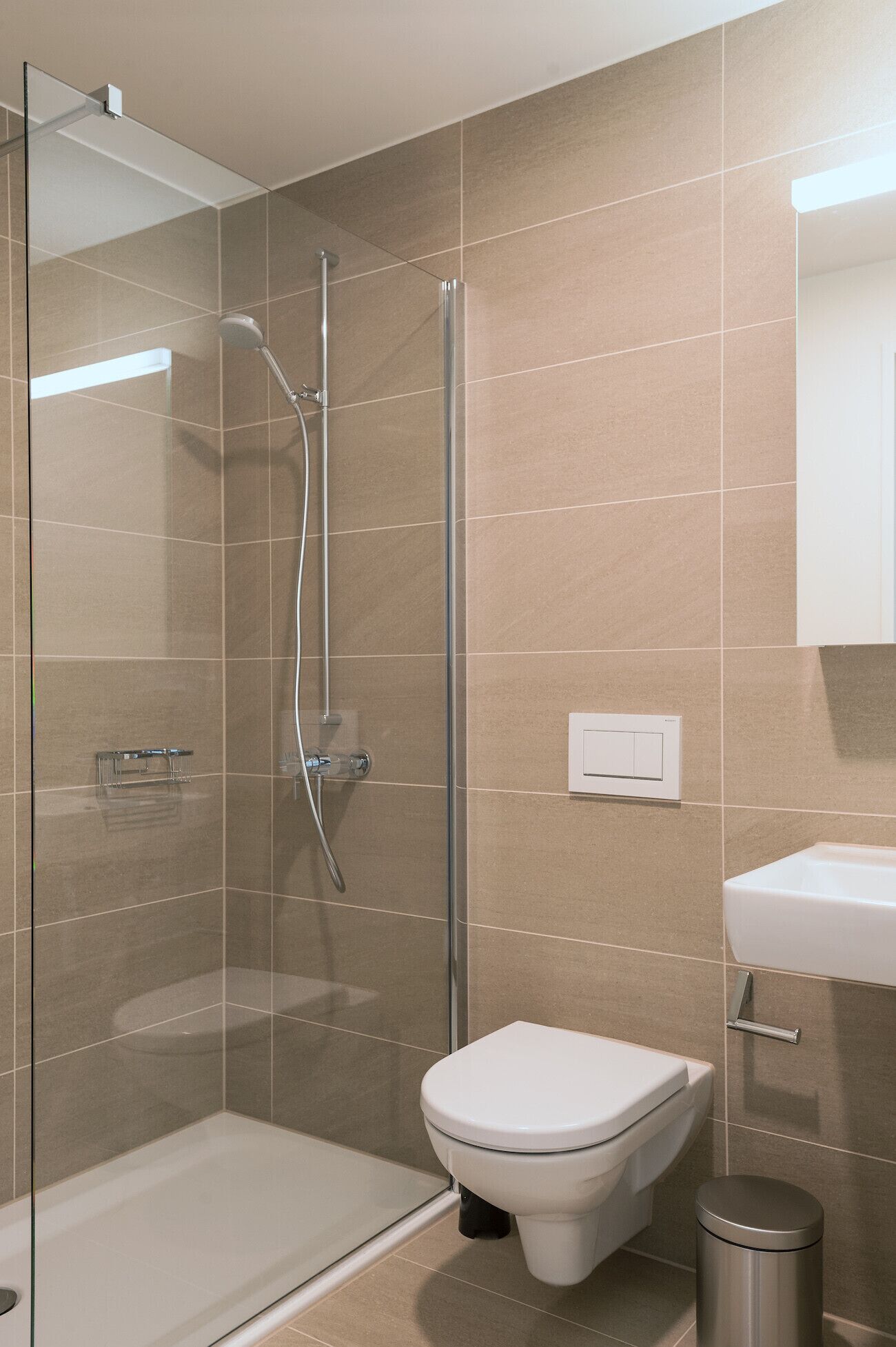 A modern bathroom with a glass shower enclosure, a white toilet, and a sink.