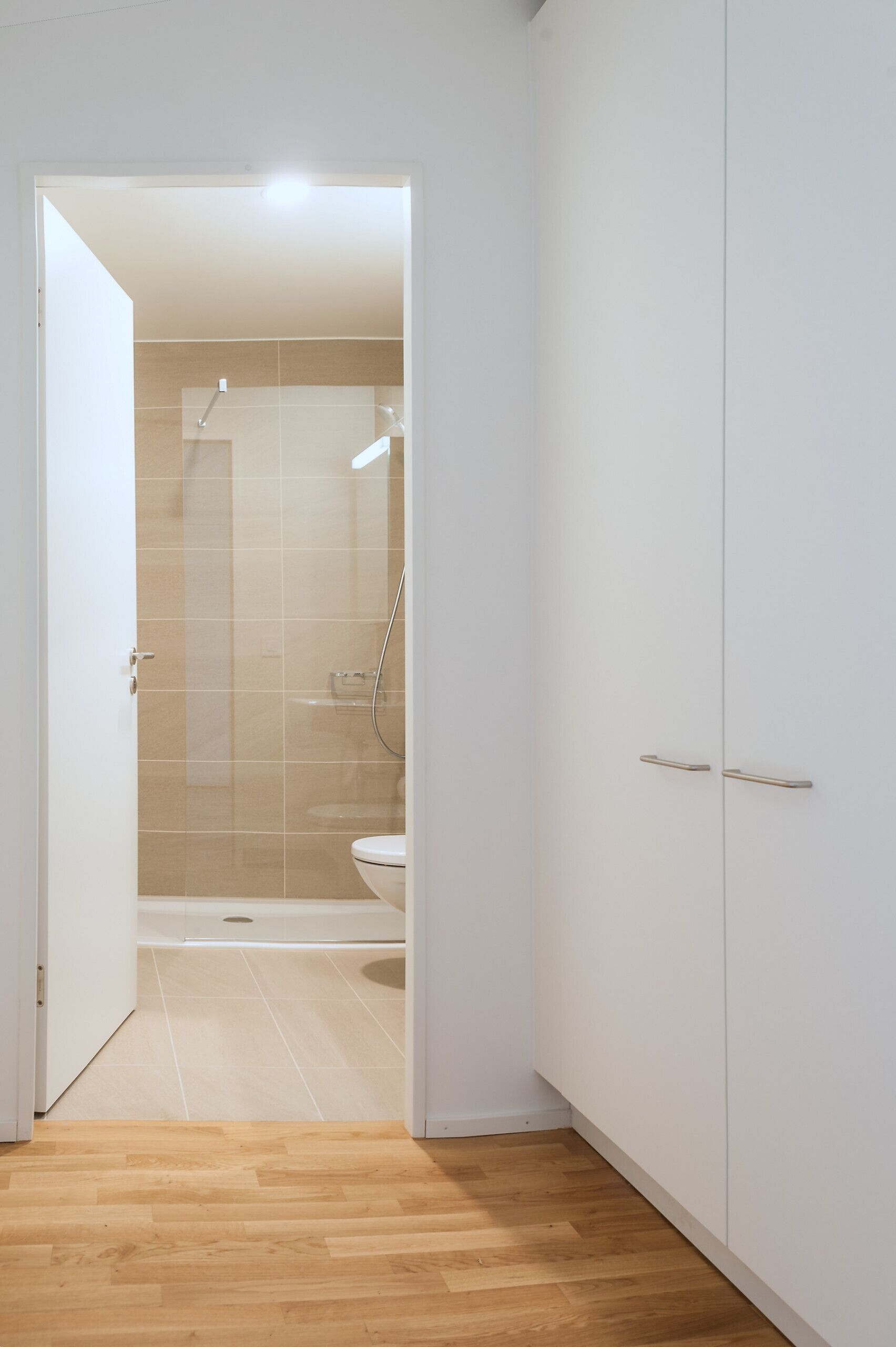 A modern bathroom with a shower, toilet, and white cabinetry.