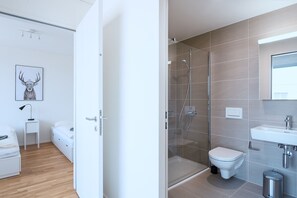 A modern bathroom with a glass-enclosed shower, a toilet, and a sink. - Hitrental Messe Apartments (Basel)