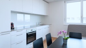 Una cocina moderna con armarios blancos, horno empotrado y ventana.