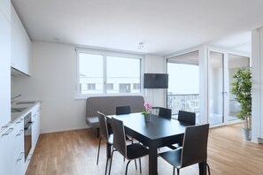 A modern apartment with a dining area, kitchen, and balcony. - Hitrental Messe Apartments (Basel)