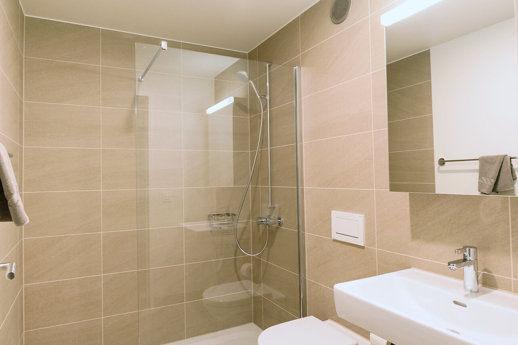 A bathroom with a glass-enclosed shower, a white sink, and a towel hanging on a rack.