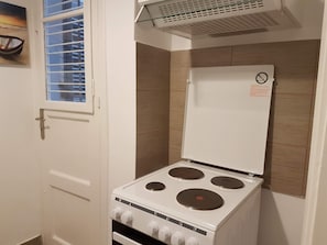 Compact kitchen with a stove, oven, and window with blinds.