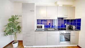 Uma cozinha moderna com armários cinza, micro-ondas, fogão e painel de azulejos azuis.
