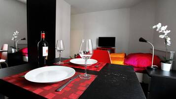A dining area with a table set for two, a bottle of wine, and two wine glasses.