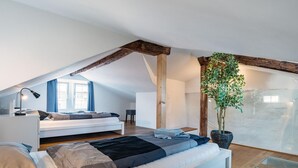 Une chambre de style loft moderne, avec un plafond en pente, une grande fenêtre et une plante en pot.