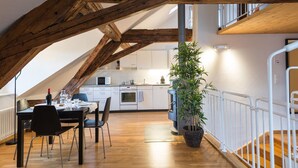 Una cocina moderna con armarios blancos, techo de madera y una zona de comedor con mesa y sillas.