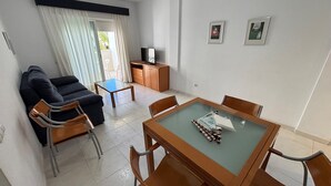 Un soggiorno con divano, tavolino, televisione e zona pranzo con sedie e tavolo.