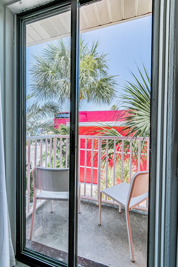 A balcony with a white chair and a red building in the background.