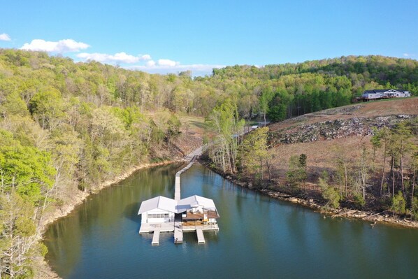 A houseboat on a river surrounded by forested hills.