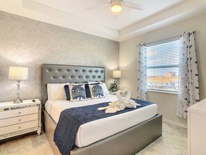 A bedroom with a bed, nightstands, a ceiling fan, and a window with curtains.