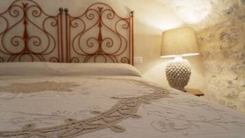 Un letto con una testiera in metallo decorata, una parete dalla texture particolare e una lampada su un comodino.
