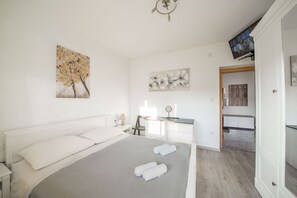 A modern bedroom with a large bed, a desk, and a TV mounted on the wall. - Spacious 3BR Beach Apartment in Zadar (Zadar)