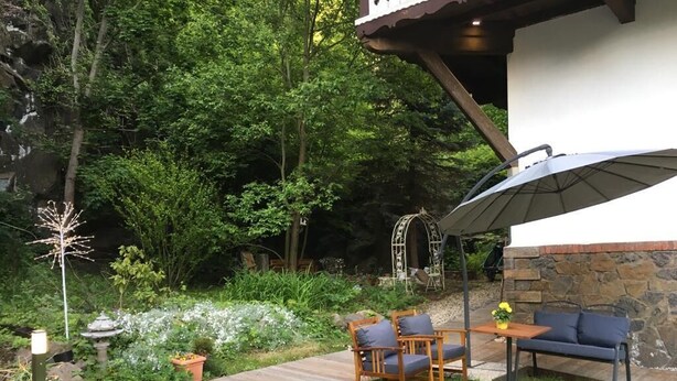 Un espace patio doté d’une terrasse en bois, de mobilier d’extérieur et d’un mur en pierre.