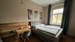 Une chambre avec un lit, un bureau et une chaise. Il y a trois tableaux accrochés au mur.