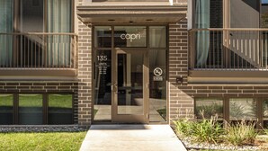 A multi-story building with a glass entrance, balconies, and a sign indicating 135 units. - Downtown Escape 1BR Condo (Traverse City)