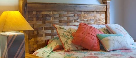 A bed with a wooden headboard, a bedside lamp, and multiple pillows.