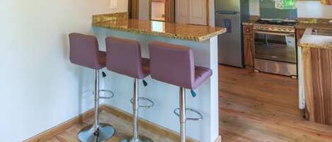 A modern kitchen with wooden cabinets, a central island with bar stools, and ceiling fans.