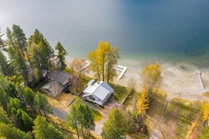 An aerial view of a lakeside property with a house, a dock, and surrounding trees.