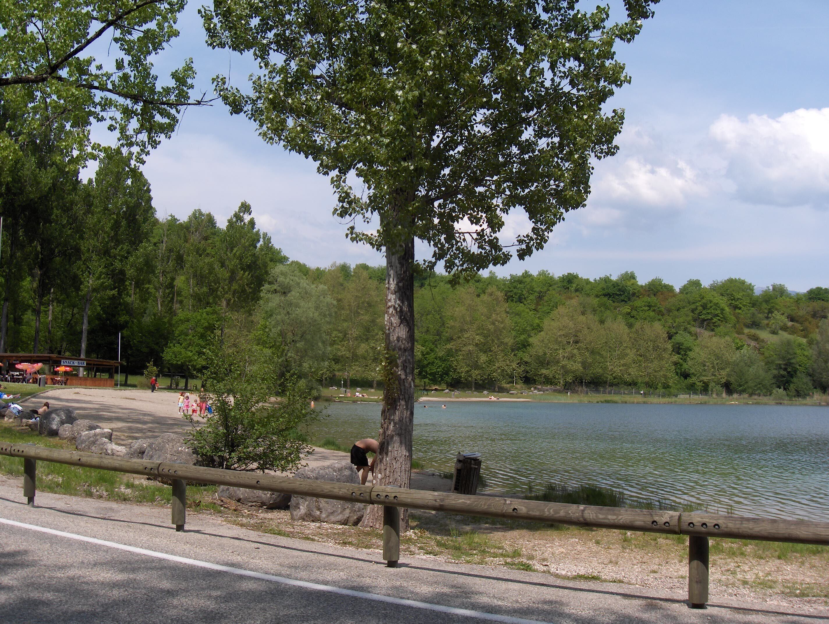 A lakeside view with a wooden fence, a snack bar, and a picnic area.