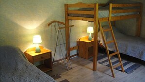 Une chambre avec un lit superposé, deux tables de chevet, chacune équipée d’une lampe, et une échelle.