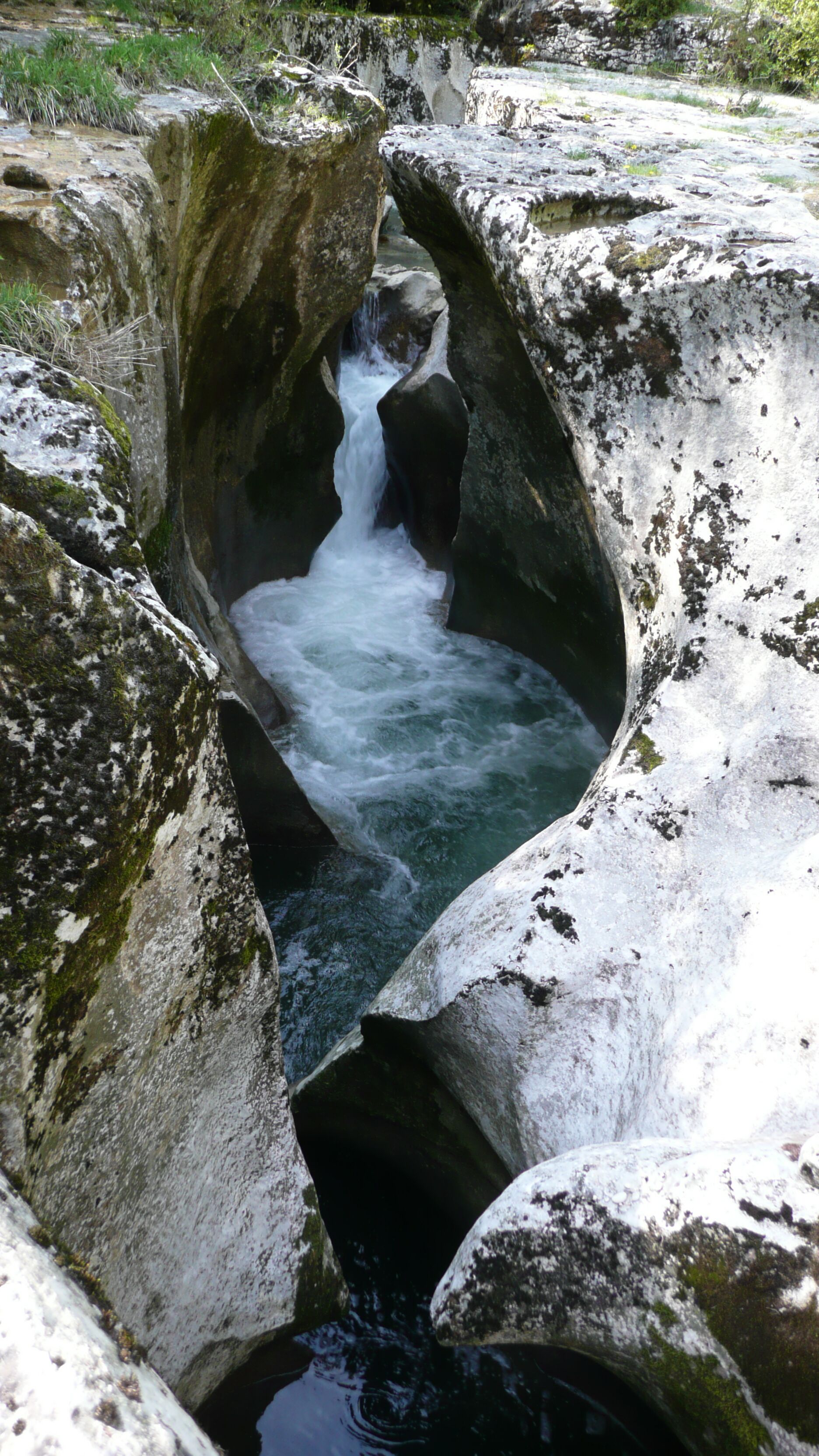 A natural rock formation with a waterfall flowing through a narrow passage.
