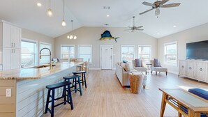 Une cuisine spacieuse dotée d’un grand îlot central, de tabourets de bar et d’un ventilateur de plafond.