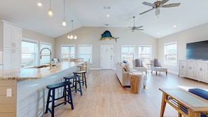A spacious kitchen with a large island, bar stools, and a ceiling fan.