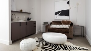 Ein modernes Wohnzimmer mit einer Couch, Hocker und einem Teppich.