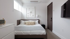 Une chambre à coucher moderne avec un lit, une table de chevet et un téléviseur fixé au mur.