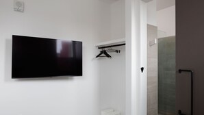 Une salle de bain moderne équipée d’un téléviseur mural, d’une douche à parois de verre et d’un porte-serviettes.