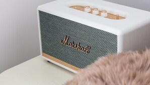 Un haut-parleur Marshall blanc, doté d’un panneau avant texturé et d’un objet duveteux au premier plan.