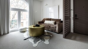 Un salon moderne avec une grande fenêtre, un canapé marron, une table basse ronde et un tapis à motifs zébrés.