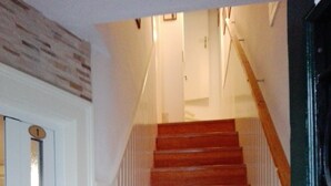 Una escalera de madera con paredes blancas y una puerta a la izquierda.