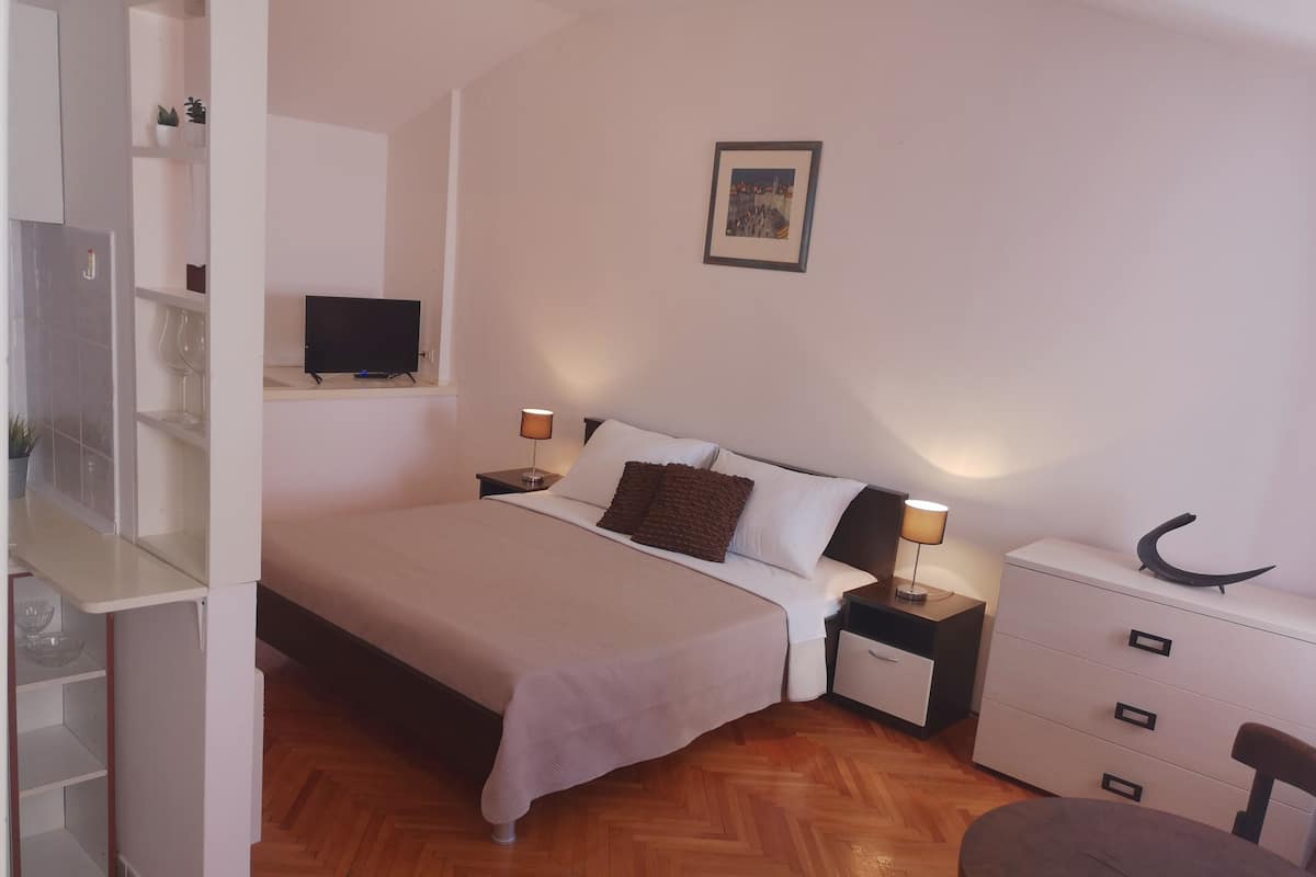 A bedroom with a bed, bedside tables, a TV, a dresser, and a chair.