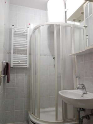 Un baño con cabina de ducha, lavabo y perchero para toallas.